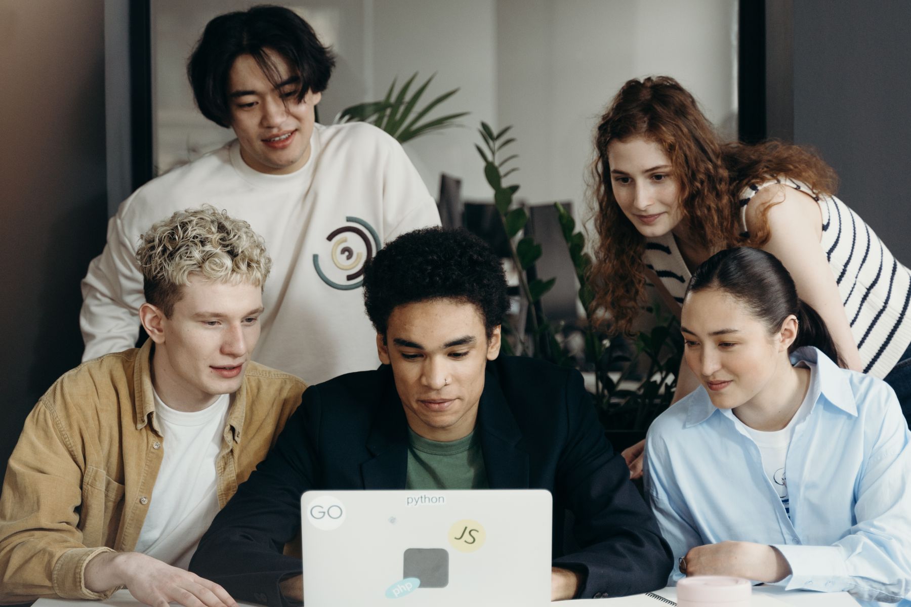 A diverse creative team collaborating around a laptop